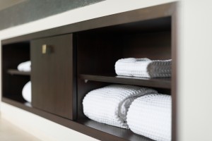 Folded white towels stored neatly on a shelf in a modern cabinet.