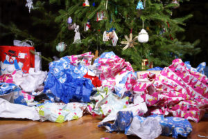 Piles of colorful gift wrapping paper scattered around the base of a decorated christmas tree.