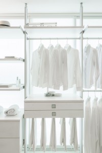 A bright and orderly closet displaying a collection of white shirts and pants.
