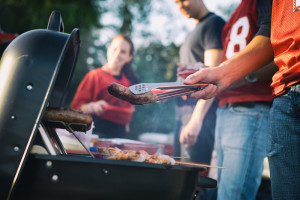 Grilling sausages and skewers at an outdoor gathering.