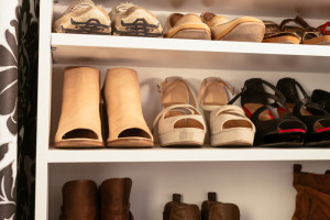 A variety of women's shoes organized on a white shelving unit.