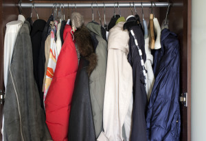 A variety of coats and jackets hanging in a closet.