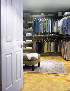 A well-organized walk-in closet with an assortment of clothes hanging, shelves with folded items, and a central ottoman.