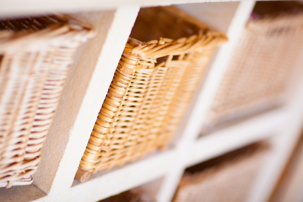 Wicker baskets stored on white wooden shelves with a shallow depth of field.