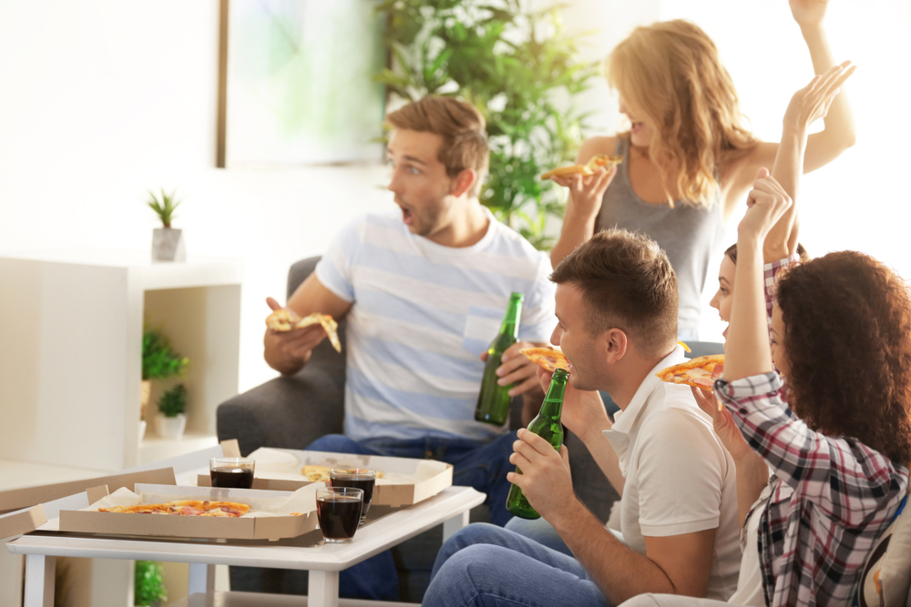 Group of friends enjoying pizza and watching tv together.