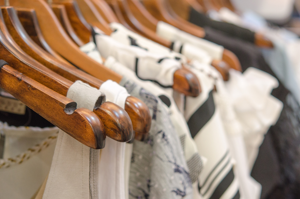 Clothes on wooden hangers in a retail store.