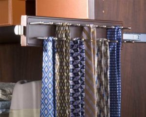 An assortment of neckties hanging on a tie rack inside a wardrobe.