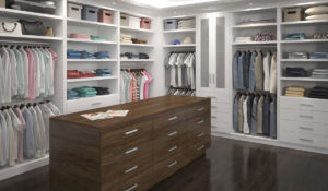 A well-organized walk-in closet with an array of neatly arranged clothes and a central island drawer unit.