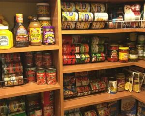 A pantry shelf stocked with various condiments and canned goods.
