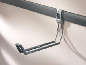 Under-desk keyboard tray mounted on a rail against a beige wall.
