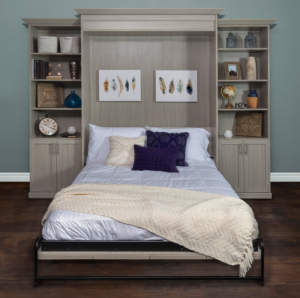 Wall bed. A murphy bed with attached shelving units, folded down in a room with decorative items displayed.