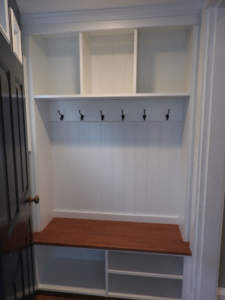 A built-in mudroom nook with a wooden bench and hooks for coats.