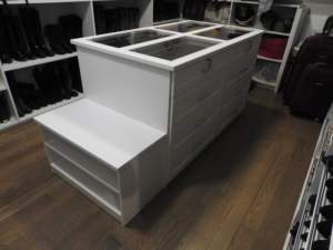 A white retail display unit with drawers in a shoe store.