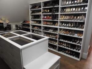 A well-organized closet dedicated to shoe storage with a white central island and shelves.