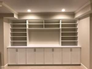 Built-in white shelving and cabinet unit in an empty room.