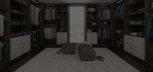 A blurred image of an open walk-in closet with clothing items and seating.