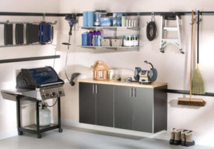 Organized garage space with storage cabinets, wall-mounted shelves, and a grilling station.