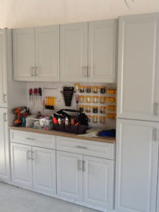 A well-organized garage workshop with tools hanging on a pegboard and parts stored in bins.