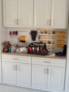 A well-organized garage workshop with tools and supplies neatly arranged on a pegboard and countertops.