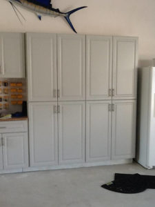 White storage cabinets in a garage with a blue marlin fish mount on the wall above.