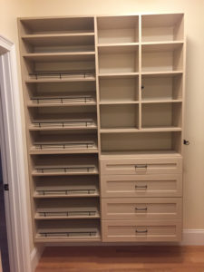 Empty wooden shelving unit with drawers and shelves in a room.