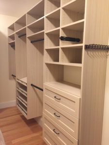 Empty wooden closet organizer with shelves and drawers.