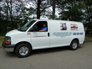 A man sitting in a white commercial van with 'boston closet co.' branding and contact information on the side.