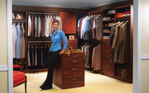 Woman standing proudly in a well-organized walk-in closet.