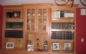 Wooden bookcase filled with books and personal memorabilia in a home interior.