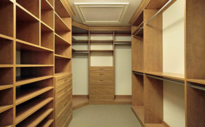 An empty walk-in closet with wooden shelves and drawers.