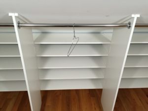 Empty white closet with a single wire hanger on a metal rod.