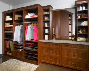 Organized walk-in closet with wooden cabinetry and neatly arranged clothes and accessories.