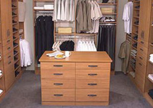 Organized walk-in closet with a central island drawer unit and neatly arranged clothes.