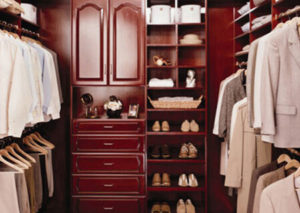 An organized walk-in closet with clothes, shoes, and accessories stored neatly on shelves and hanging spaces.