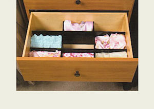 An open wooden drawer with clothes neatly organized into sections.
