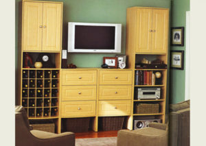 A living room with a wooden entertainment unit featuring a tv, storage cabinets, and shelves with various decorative items, flanked by two armchairs.