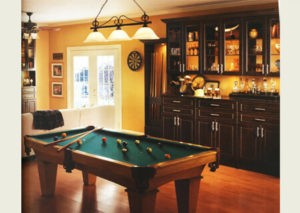 Cozy game room with a billiard table, warm lighting, and wooden cabinetry.