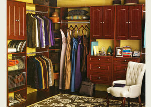 An organized walk-in closet with clothes, shoes, and a seating area.