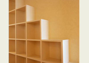 Empty wooden shelves against a yellow wall.
