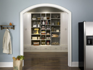 A well-organized kitchen pantry with labeled shelves and a modern refrigerator to the right.