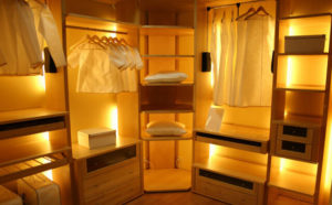 Compact and organized capsule hotel room with warm lighting.