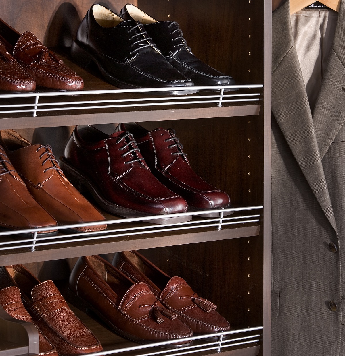 An array of men's dress shoes and a suit displayed in a wooden closet.