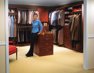 A woman standing in a well-organized walk-in closet with shelves and hanging clothes.