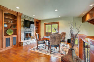 Cozy custom man cave with a fireplace and hardwood floors in a rustic setting.