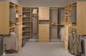 An organized walk-in closet with wooden cabinetry and clothing items hung neatly.