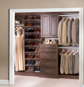 An organized walk-in closet with neatly arranged shoes, drawers, and hanging clothes.
