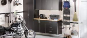 Organized garage interior with motorcycle, storage cabinets, and Attleboro Closet Organizer.