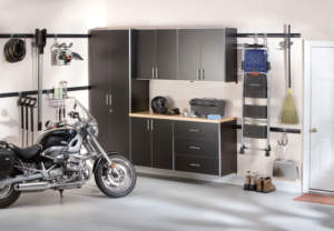 Organized garage interior with Attleboro Closet Organizer cabinets, workbench, and a motorcycle.