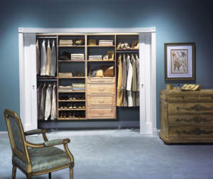 A well-organized walk-in closet with open sliding doors, featuring shelves for shoes and folded clothes, drawers, and hanging space for garments, in a room with classical décor.