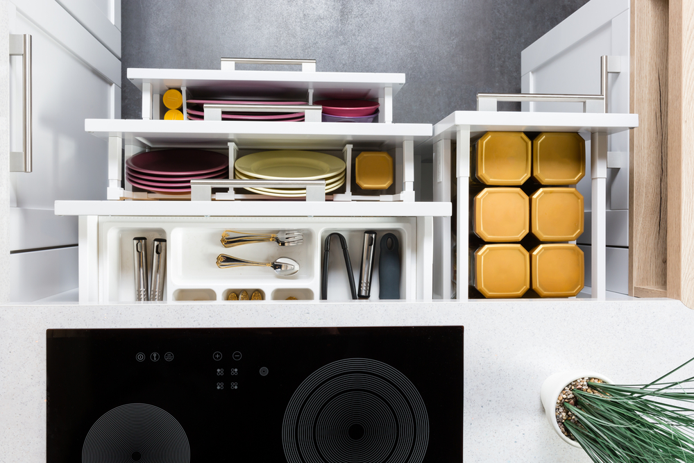 Modern kitchen cabinet with neatly organized dishes and utensils above an induction cooktop.